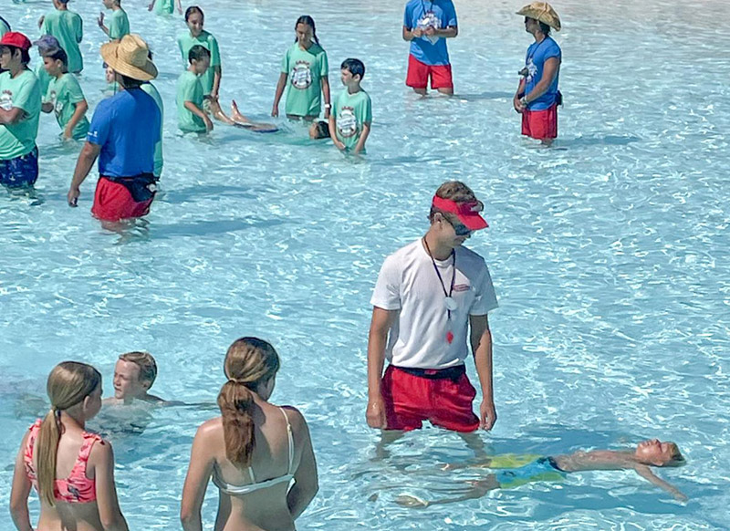 Swim instructor helps young boy float on his back.