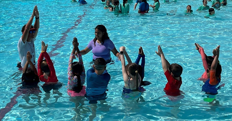 Wild Rivers swim instructor guides group of children in learning basic swimming stroke techniques.